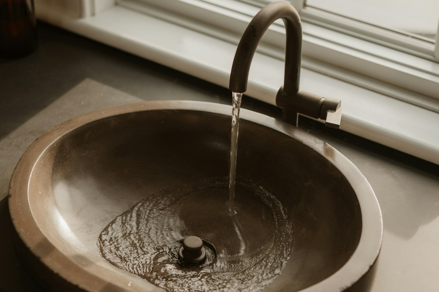 Kraan met stromend water boven een wastafel